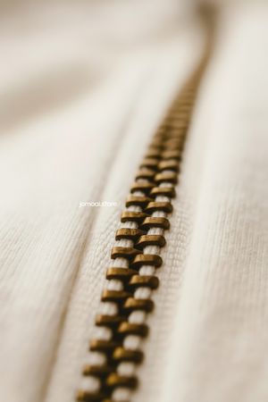 Detailed Macro Shot of Brass Zipper on Soft Beige Fabric – Textile Close-Up