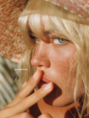 Close-Up Portrait of Freckled Woman in Straw Hat with Fingers on Lips