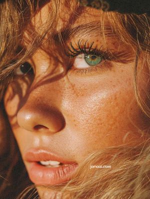 Extreme Close-Up of Freckled Woman with Windswept Hair and Bright Eyes