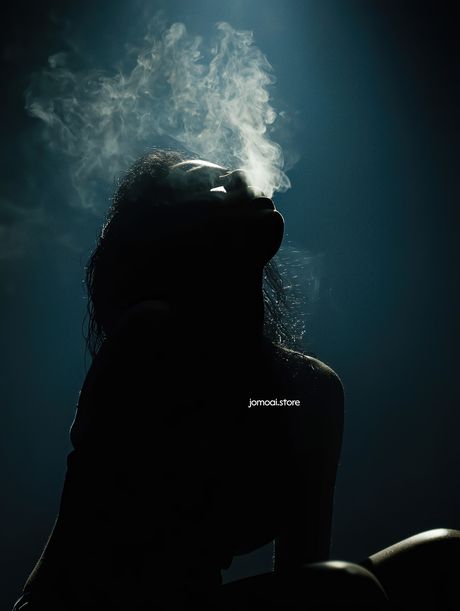 Silhouette of Woman with Rising Smoke in Moody Blue Light