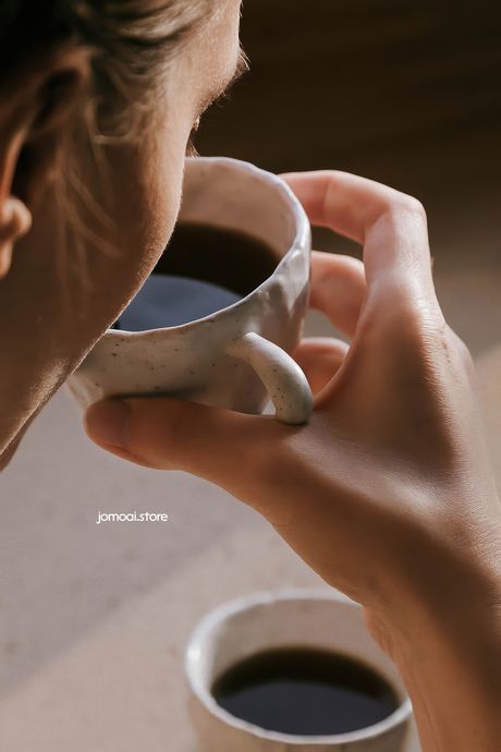 Woman drinking black coffee from handmade ceramic cup