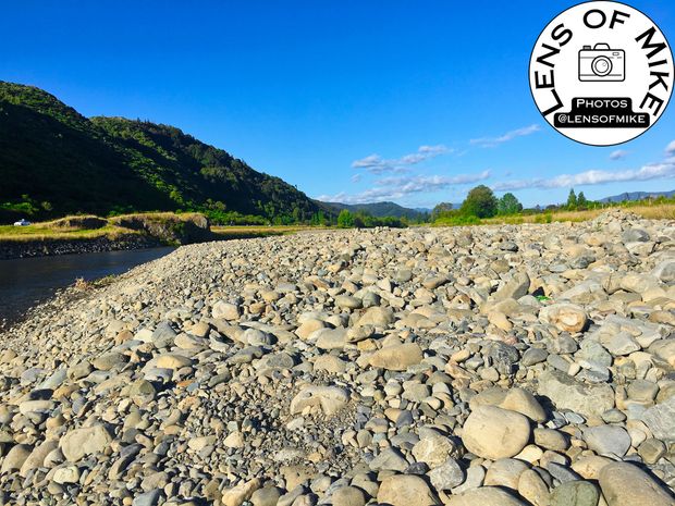 Rocky Riverbank Landscape Tranquil Nature View with Blue Sky and Green Hills Photo Download