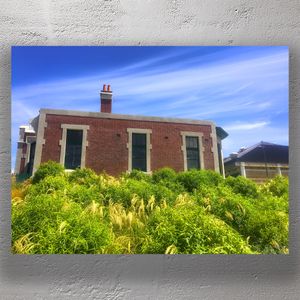 Historic Red Brick Building with Lush Greenery Under a Vibrant Blue Sky Photo Download