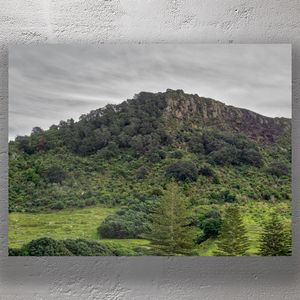 Lush Green Hillside of Mount Maunganui Under Cloudy Skies Photo Download