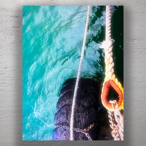Nautical Detail Worn Dock Tire Fender with Ropes Over Turquoise Water Photo Download