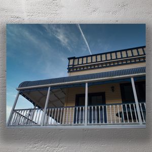 Vintage Western-Style Wooden Building with Covered Veranda and Blue Trim Photo Download