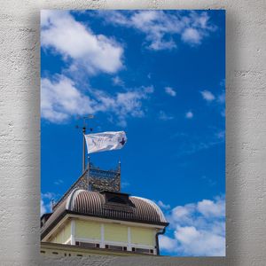 Elegant Rooftop with Weather Vane and White Flag Against a Vivid Blue Sky Photo Download