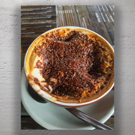 Rich Cappuccino with Chocolate Shavings in Rustic Café Setting Photo Download