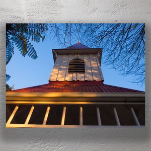 Historic Church Tower at Golden Hour with Clear Blue Sky and Tree Branches Photo Download