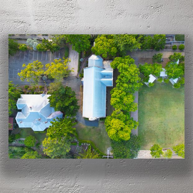 Aerial View of Historic Church with Metal Roof Surrounded by Lush Greenery Photo Download