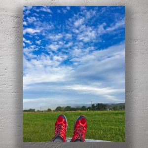 Relaxing Outdoors Feet Up with Red Running Shoes Against a Scenic Blue Sky Photo Download