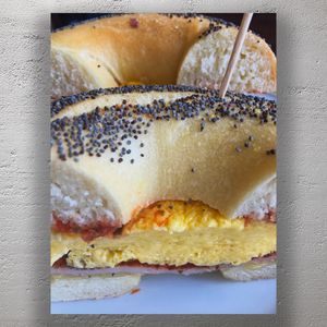 Delicious Poppy Seed Bagel Breakfast Sandwich with Egg Ham and Cheese Photo Download