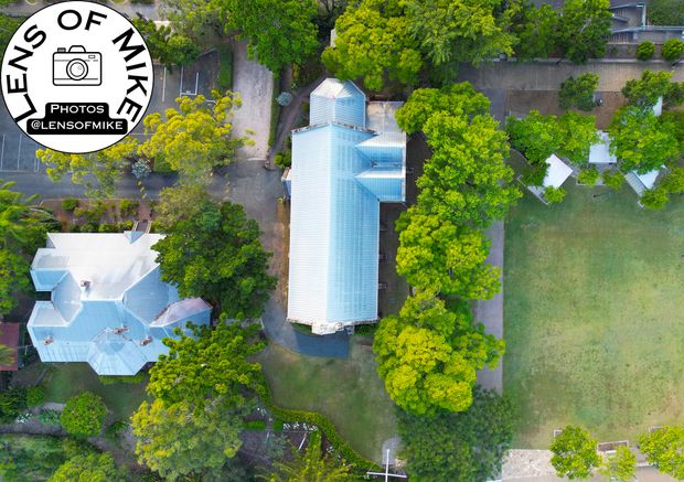 Aerial View of Historic Church with Metal Roof Surrounded by Lush Greenery Photo Download